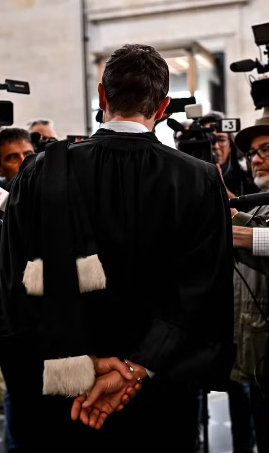 Maître Julien Plouton, en robe, face aux caméras et aux micros de la presse à l'issue d'une audience.